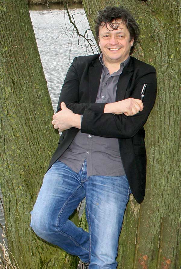 Schrijver Hans van Bergen leunt tegen boom